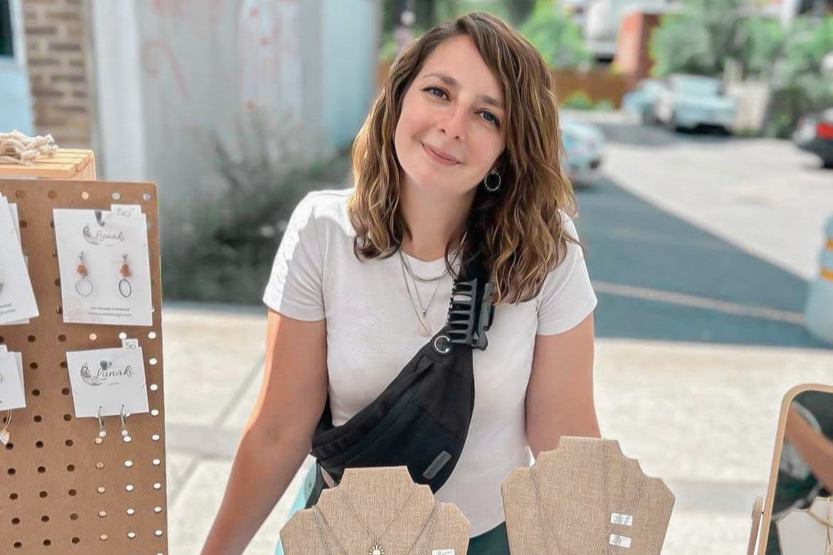 Alexia, créatrice de Lunaki Design, derrière son kiosque de bijoux artisanaux en pierres semi-précieuses lors d’un marché d’artisans à Montréal.