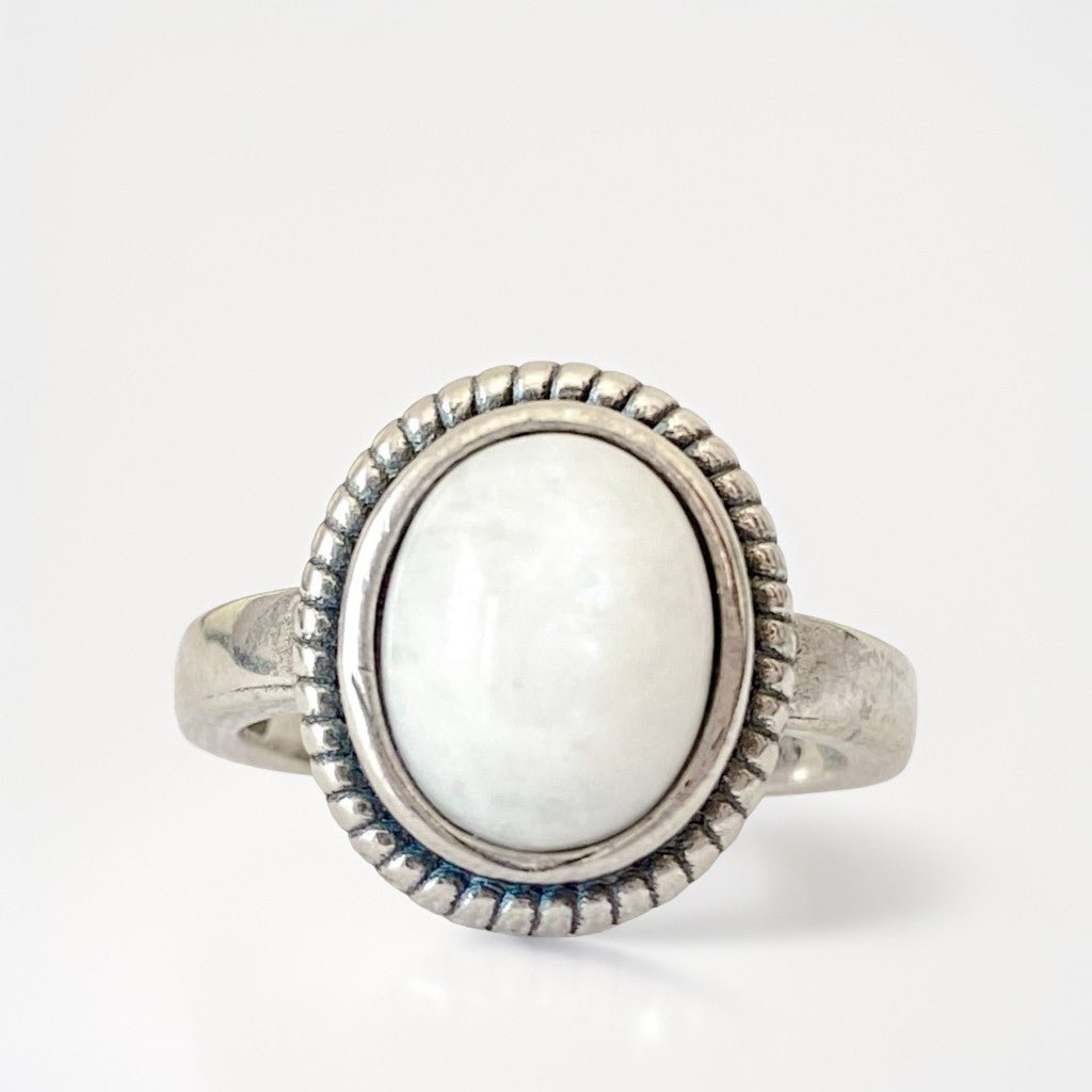 Bague en argent sterling 925 "Moonstone" sertie d'une pierre de lune arc-en-ciel ovale aux reflets bleus et argentés. Élégante et intemporelle, elle capte la lumière avec mystère. Photo de face sur fond blanc.