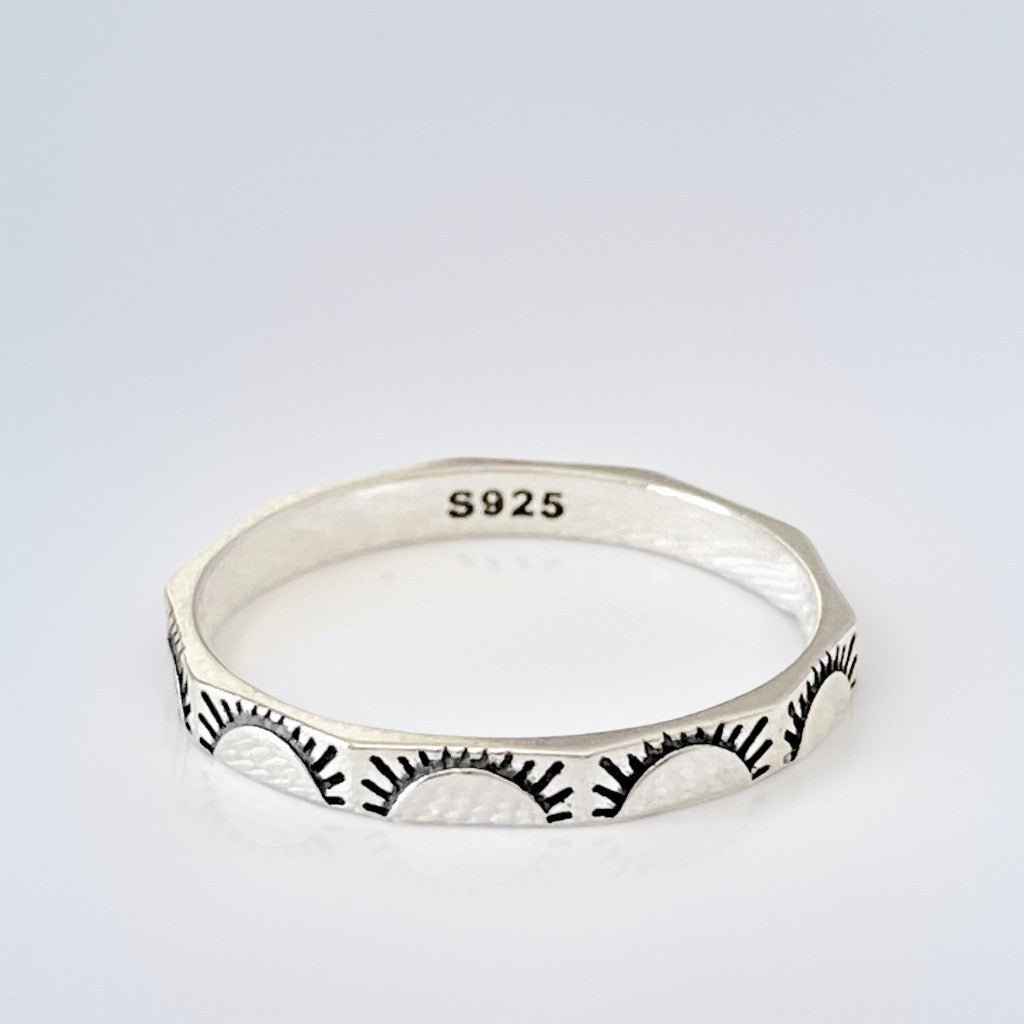 Vue de dessus de la bague en argent sterling "Sunny" avec poinçon S925 visible, mettant en valeur ses facettes gravées de soleils levants. Photo minimaliste sur fond blanc.