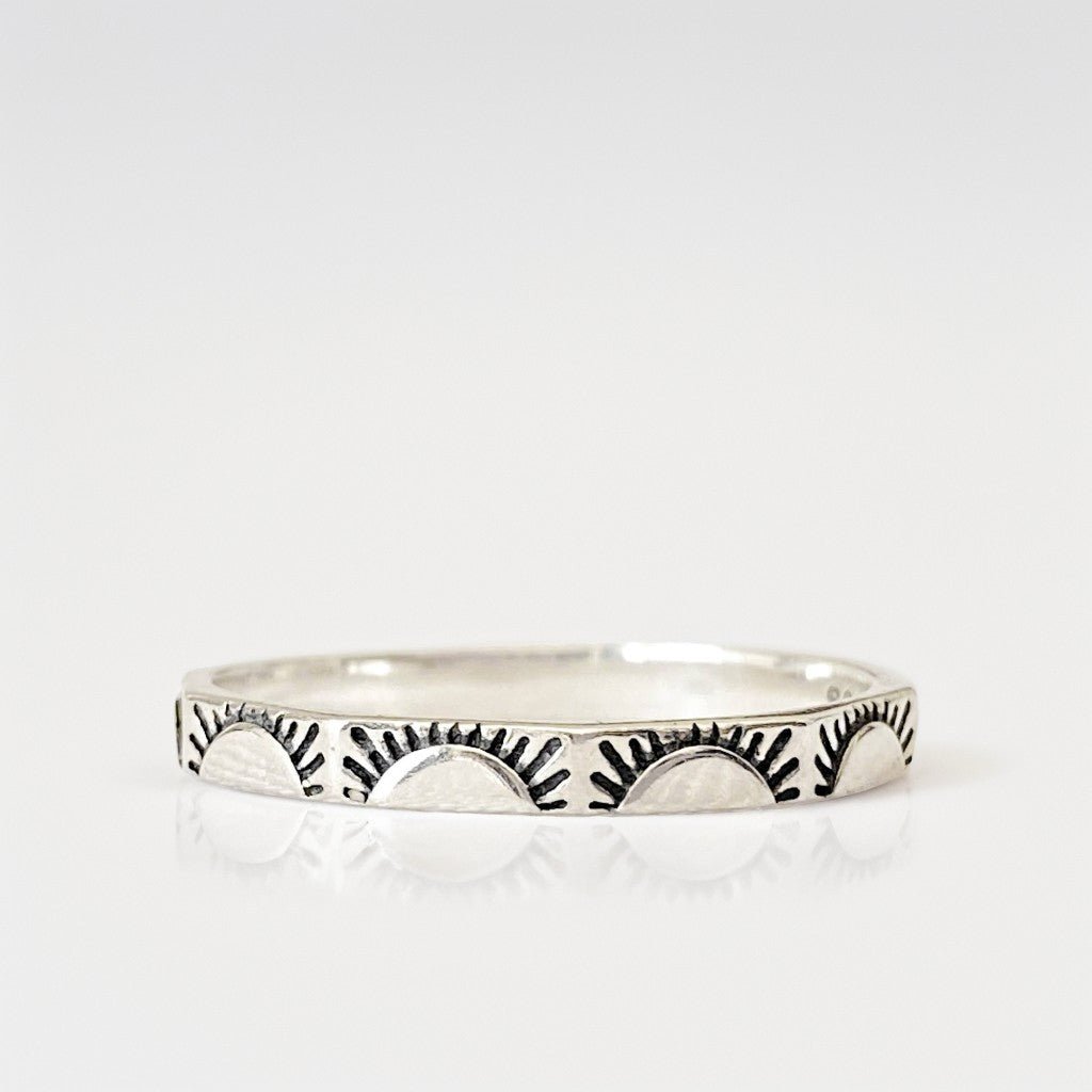 Bague en argent sterling "Sunny" avec motifs de soleils levants gravés sur chaque facette. Photo minimaliste sur fond blanc.