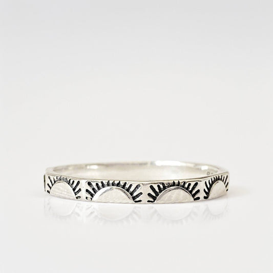Bague en argent sterling "Sunny" avec motifs de soleils levants gravés sur chaque facette. Photo minimaliste sur fond blanc.