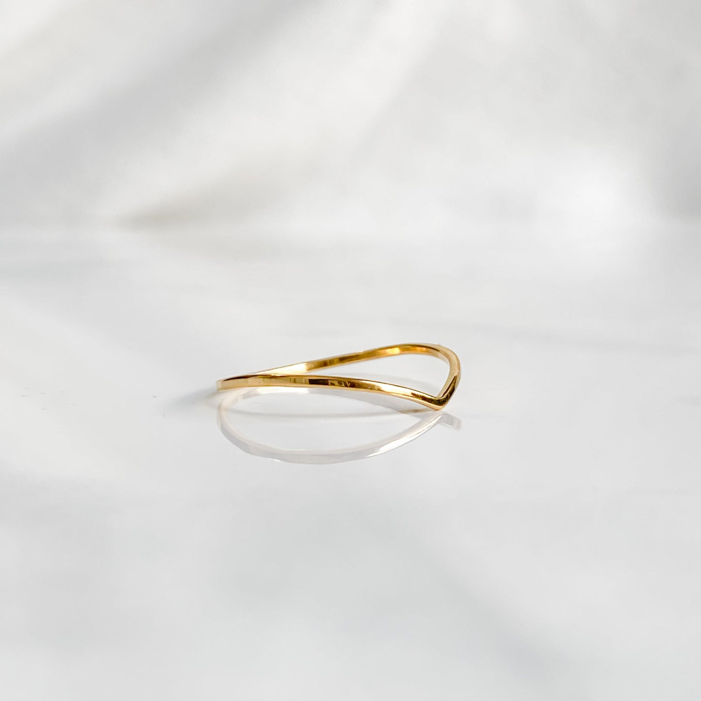 Anneau doré minimaliste Bellona en acier inoxydable plaqué or 18K présenté de biais.