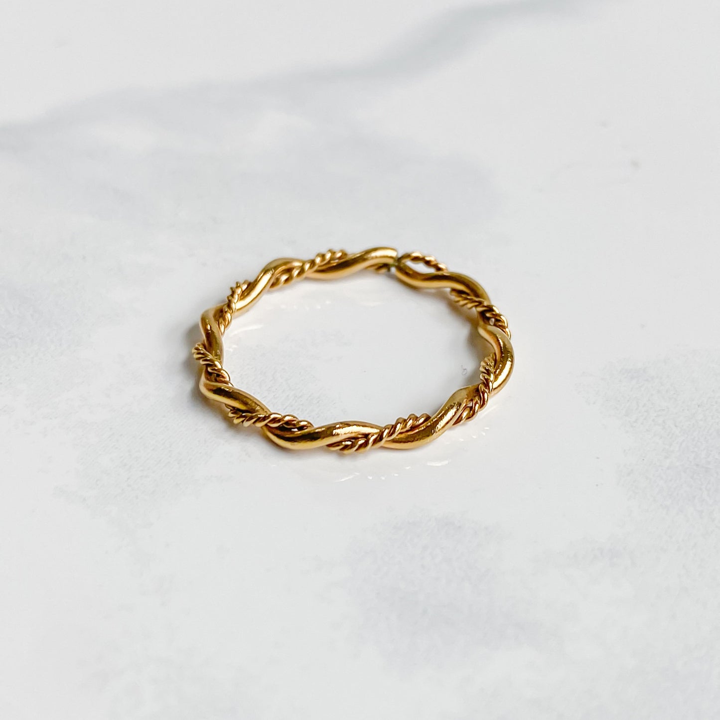 Bague Rhéa fine et minimaliste en acier inoxydable plaqué or 18K, vue inclinée sur fond blanc.