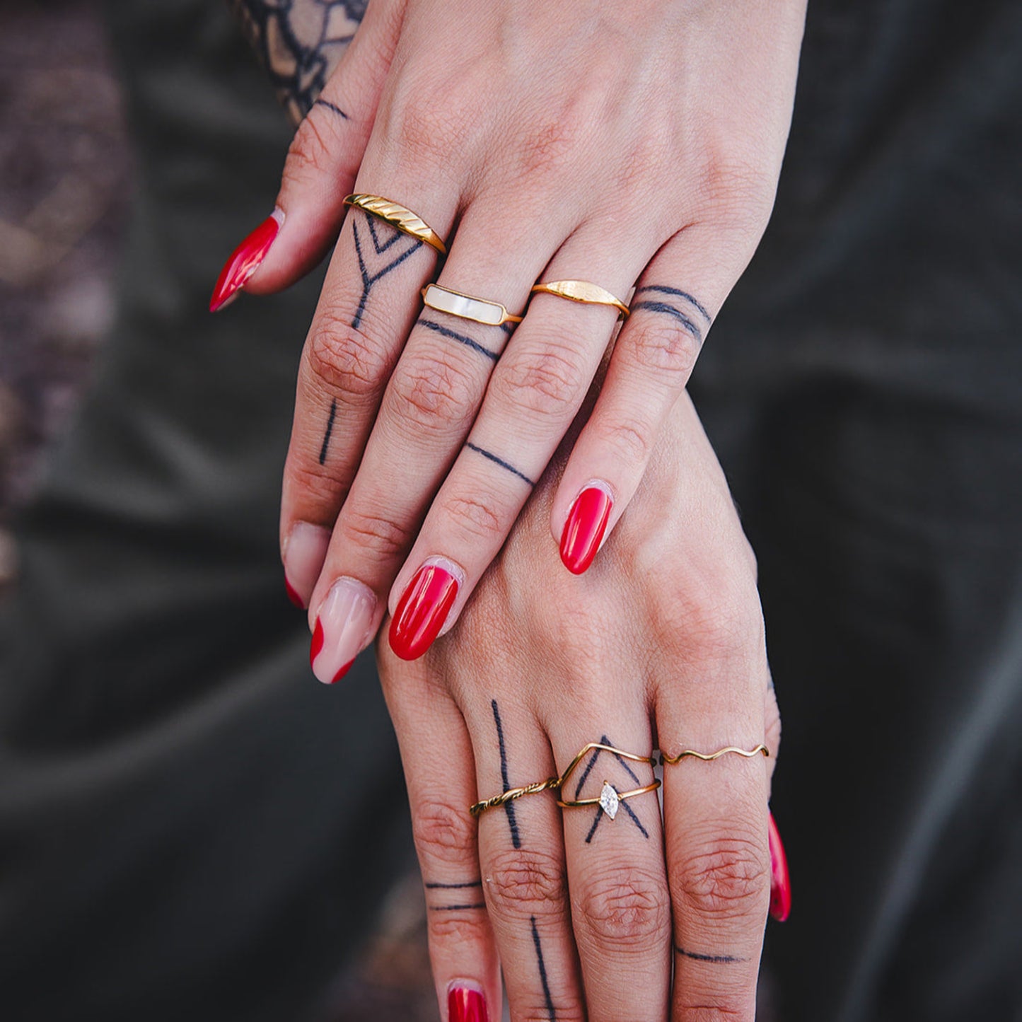 Bagues dorées tendance portées en stacking sur les mains d’une femme