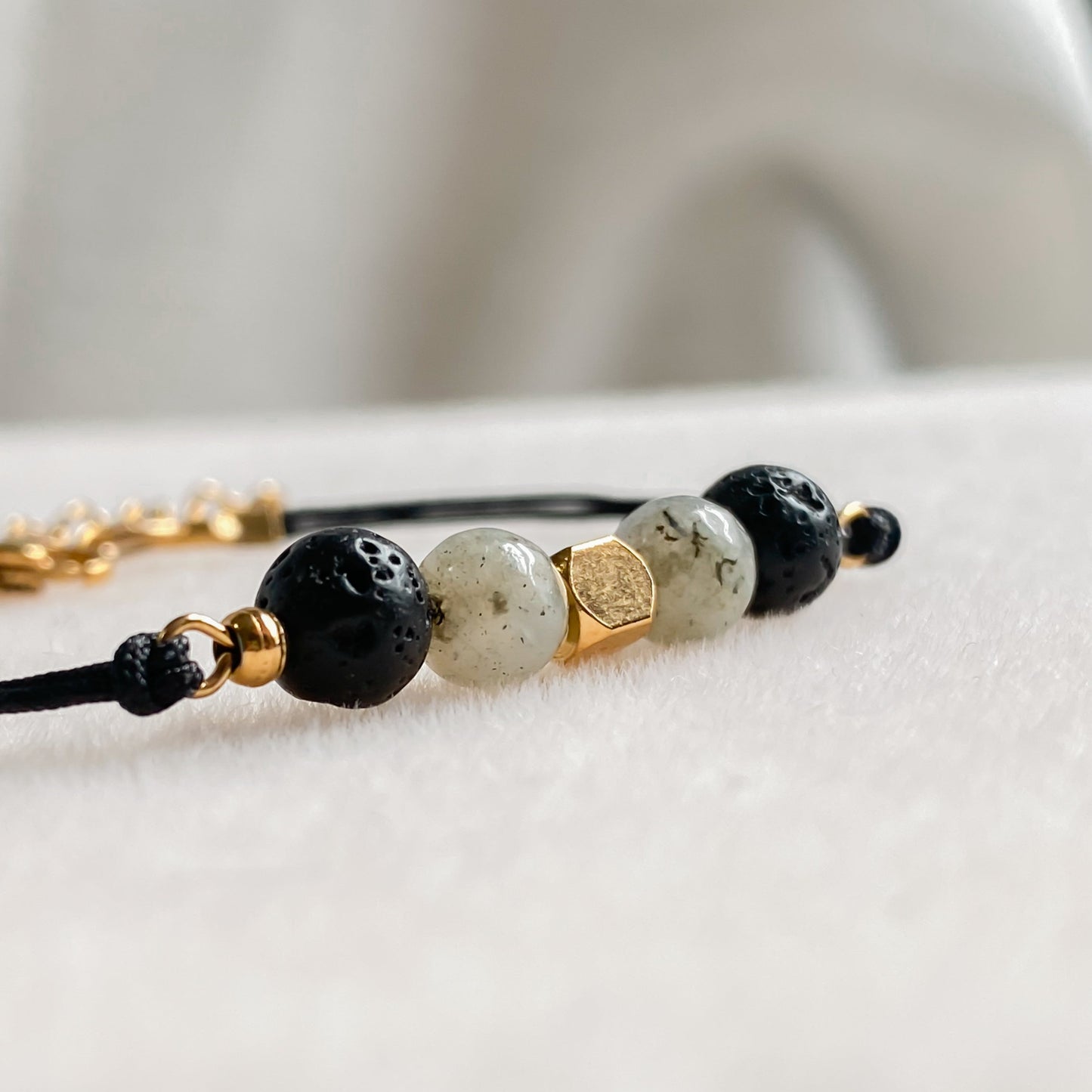 Zoom rapproché sur le bracelet NOCTIS en pierre de lave noire et labradorite, monté sur cordon noir avec apprêts dorés.