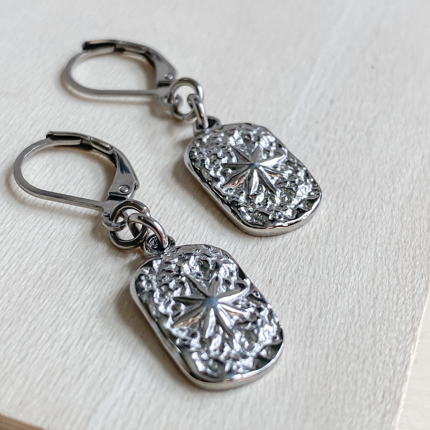 Boucles d’oreilles Estrella en acier inoxydable argenté avec pendentif étoile texturé – vue rapprochée
