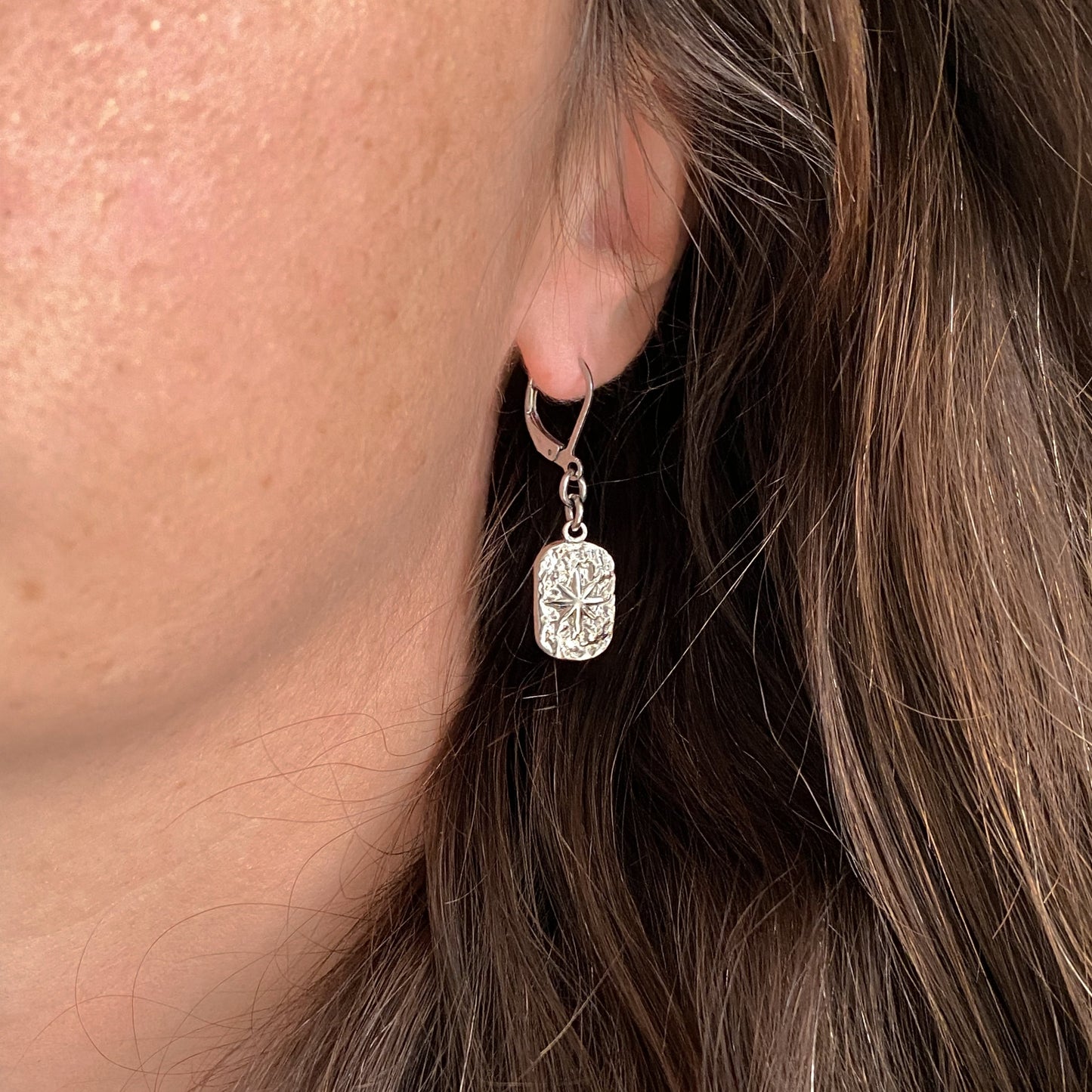 Boucles d’oreilles pendantes Estrella en acier inoxydable argenté portées à l’oreille – bijou artisanal et minimaliste