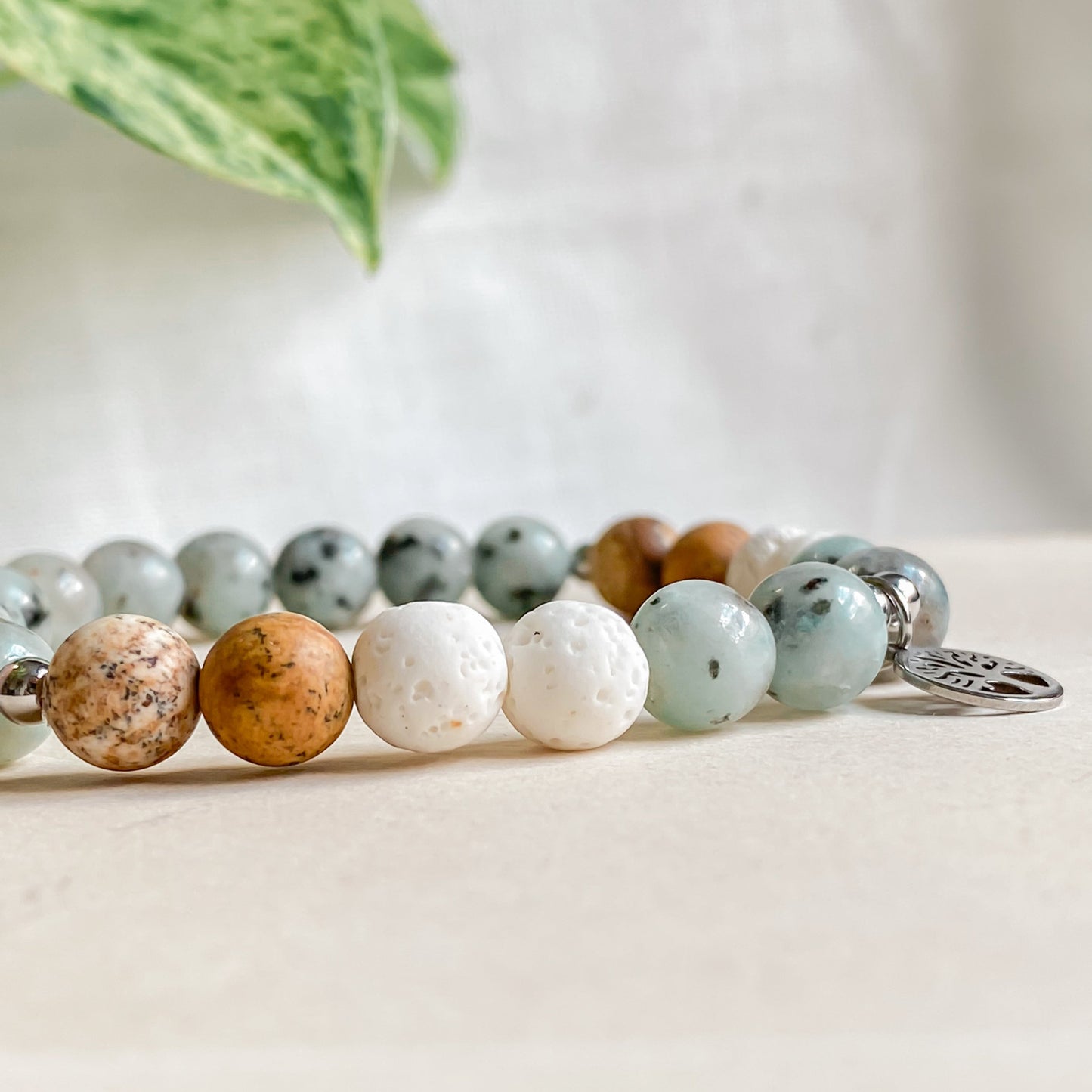 Vue rapprochée des perles jaspe paysage, pierre de lave blanche et jaspe kiwi du bracelet arbre de vie argenté.