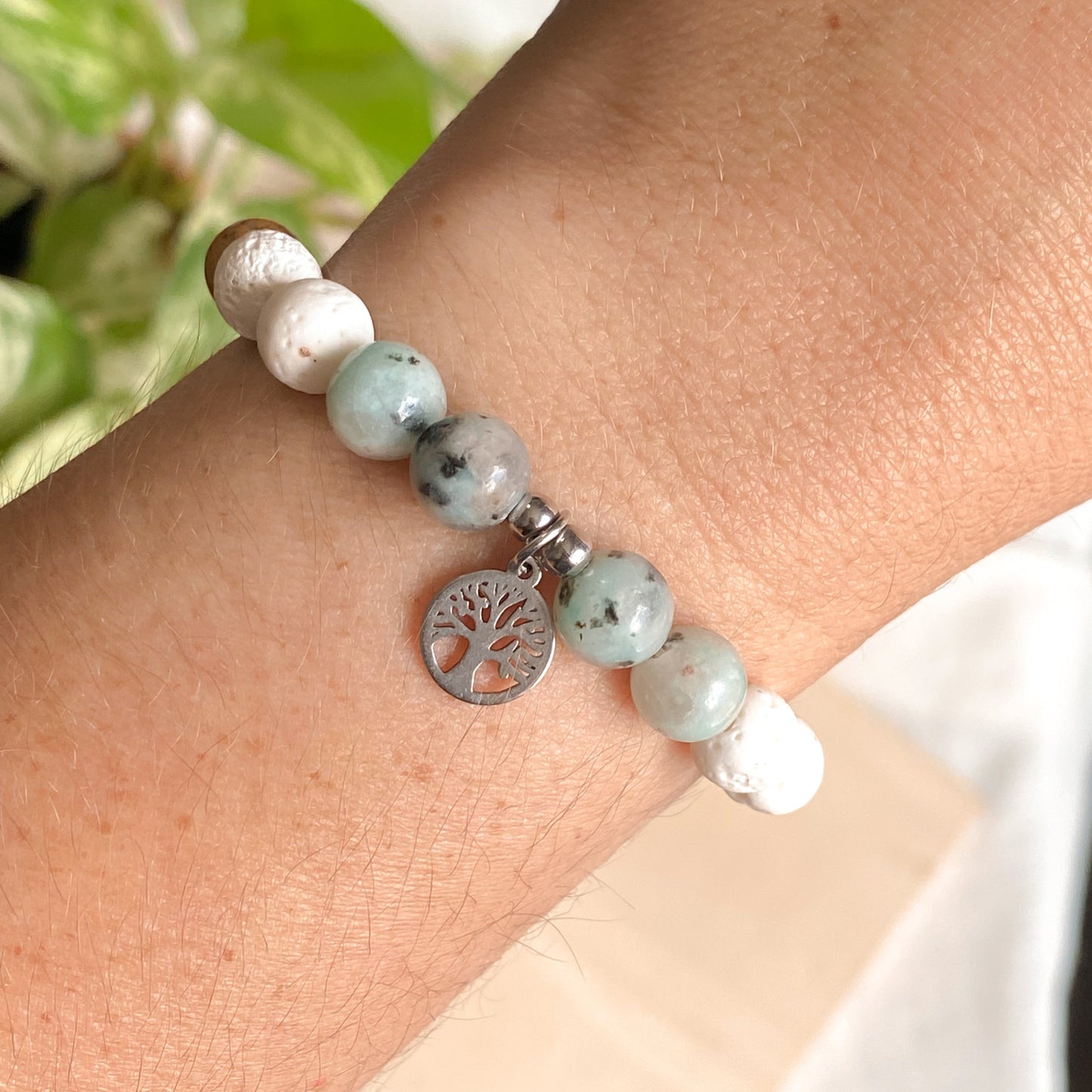 Bracelet arbre de vie porté au poignet, perles jaspe kiwi, lave blanche et pendentif argenté, bijou artisanal pour femme.