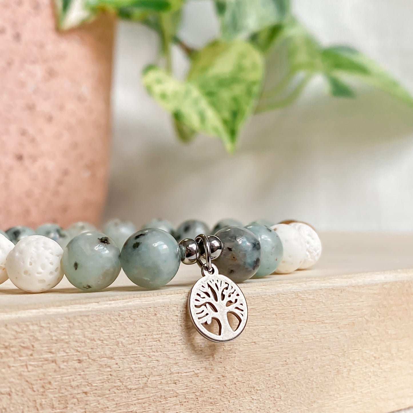 Gros plan du bracelet arbre de vie en pierres naturelles avec pendentif argenté, jaspe kiwi et perles de lave blanches.