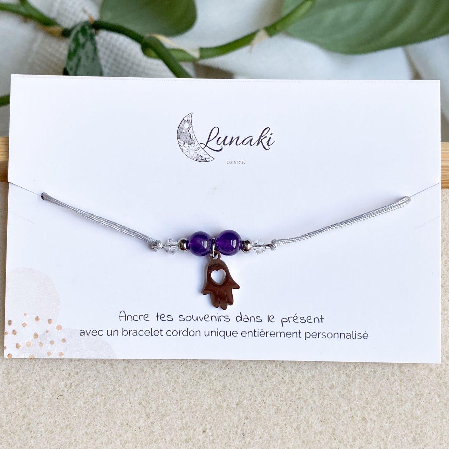 Bracelet cordon personnalisable Gardien des Souvenirs en acier argenté avec breloque Main de Fatma, présenté sur son carton d'envoi.