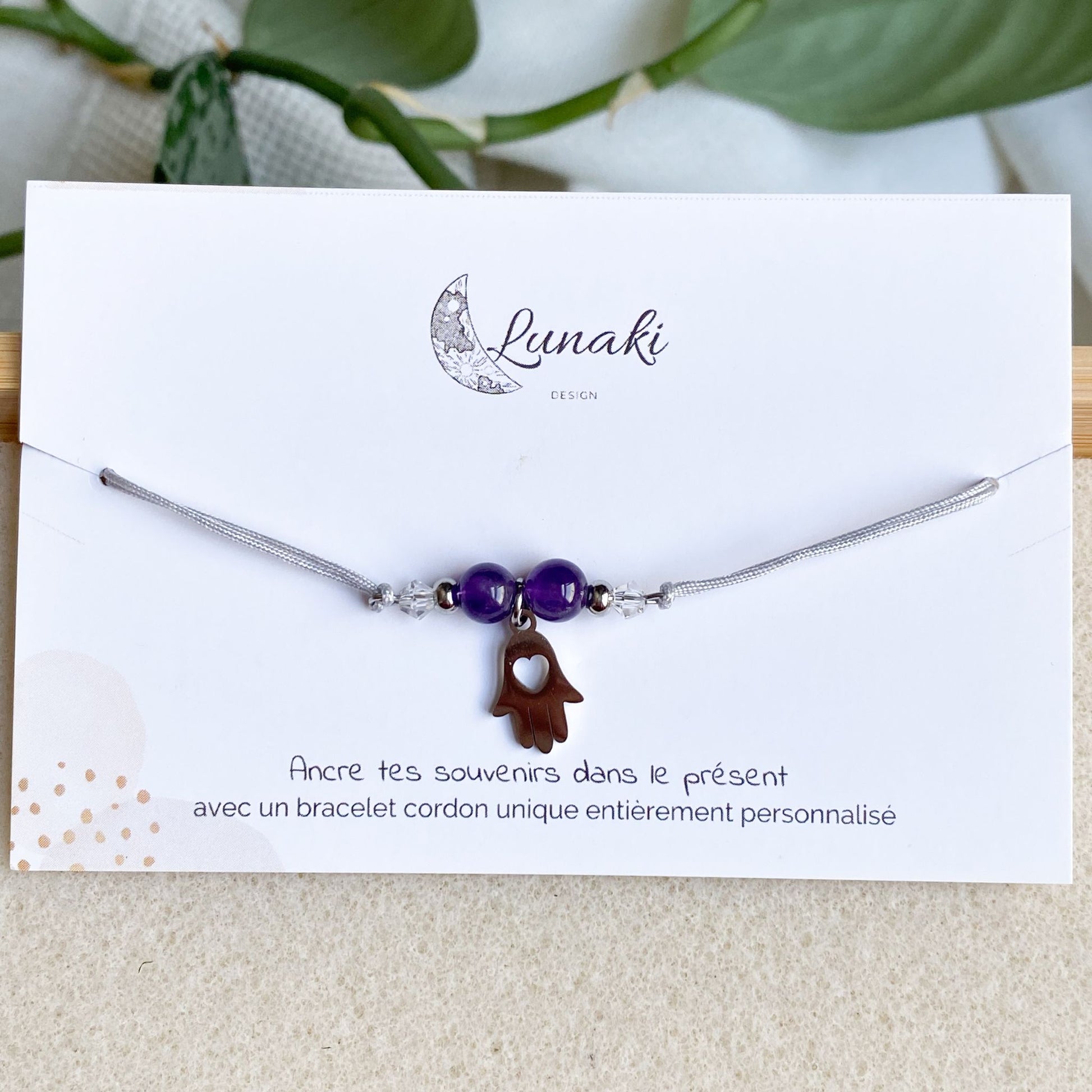 Bracelet cordon personnalisable Gardien des Souvenirs en acier argenté avec breloque Main de Fatma, présenté sur son carton d'envoi.