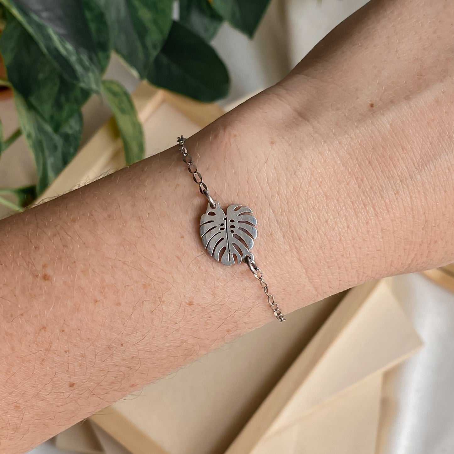 Bracelet minimaliste en chaîne fine avec pendentif feuille de monstera, élégamment porté au poignet pour un style naturel et épuré.