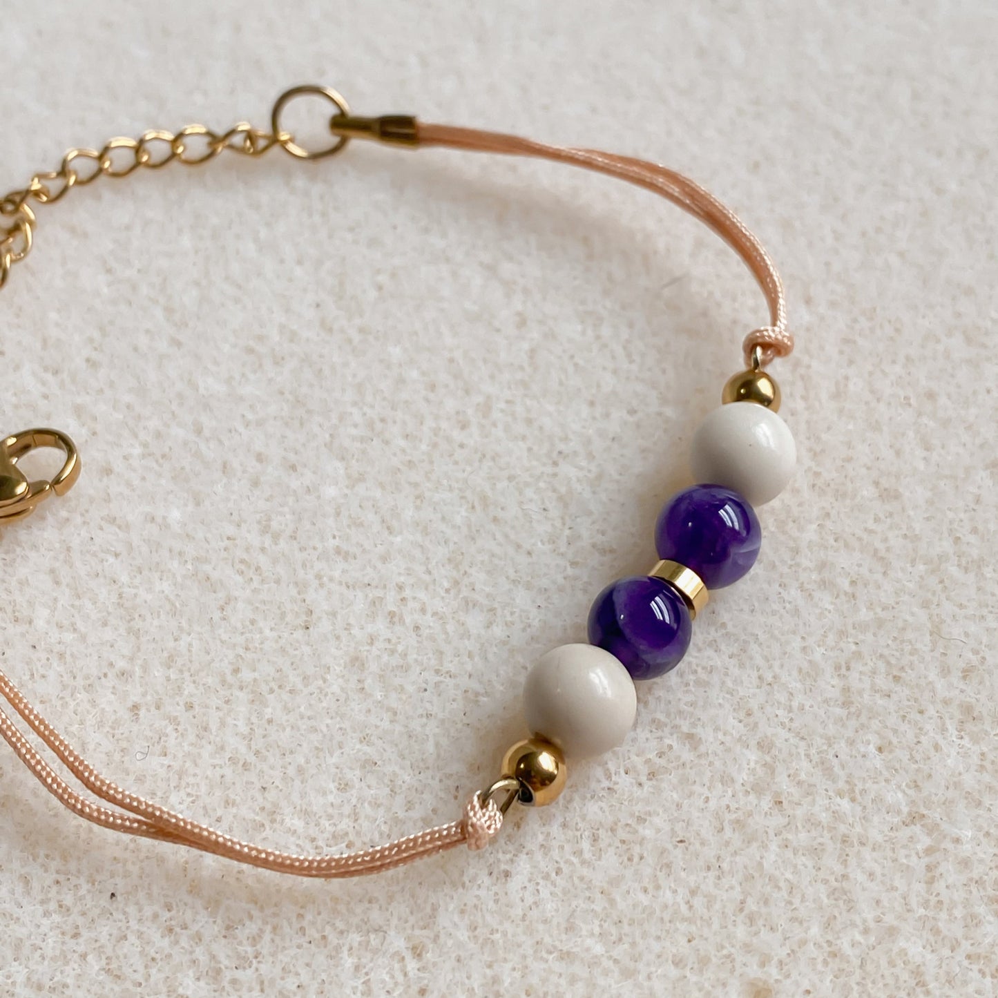 Gros plan du bracelet Zéphyr avec améthyste et pierre de rivière sur cordon ajustable champagne