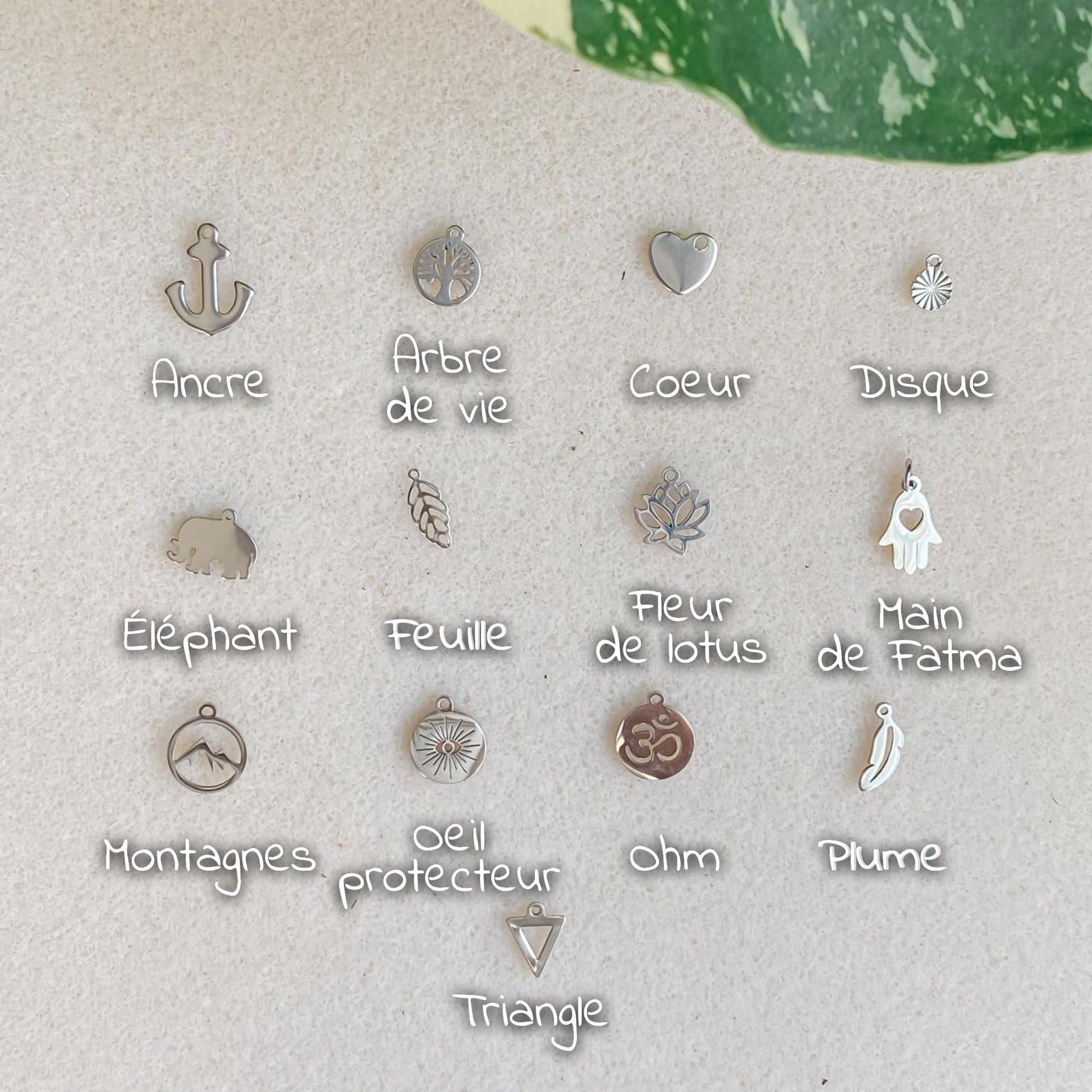 Toutes les options de breloques en acier inoxydable argenté pour bracelets cordon personnalisables, incluant ancre, arbre de vie, cœur, disque, éléphant, feuille, fleur de lotus, main de Fatma, montagnes, œil protecteur, ohm, plume, et triangle.