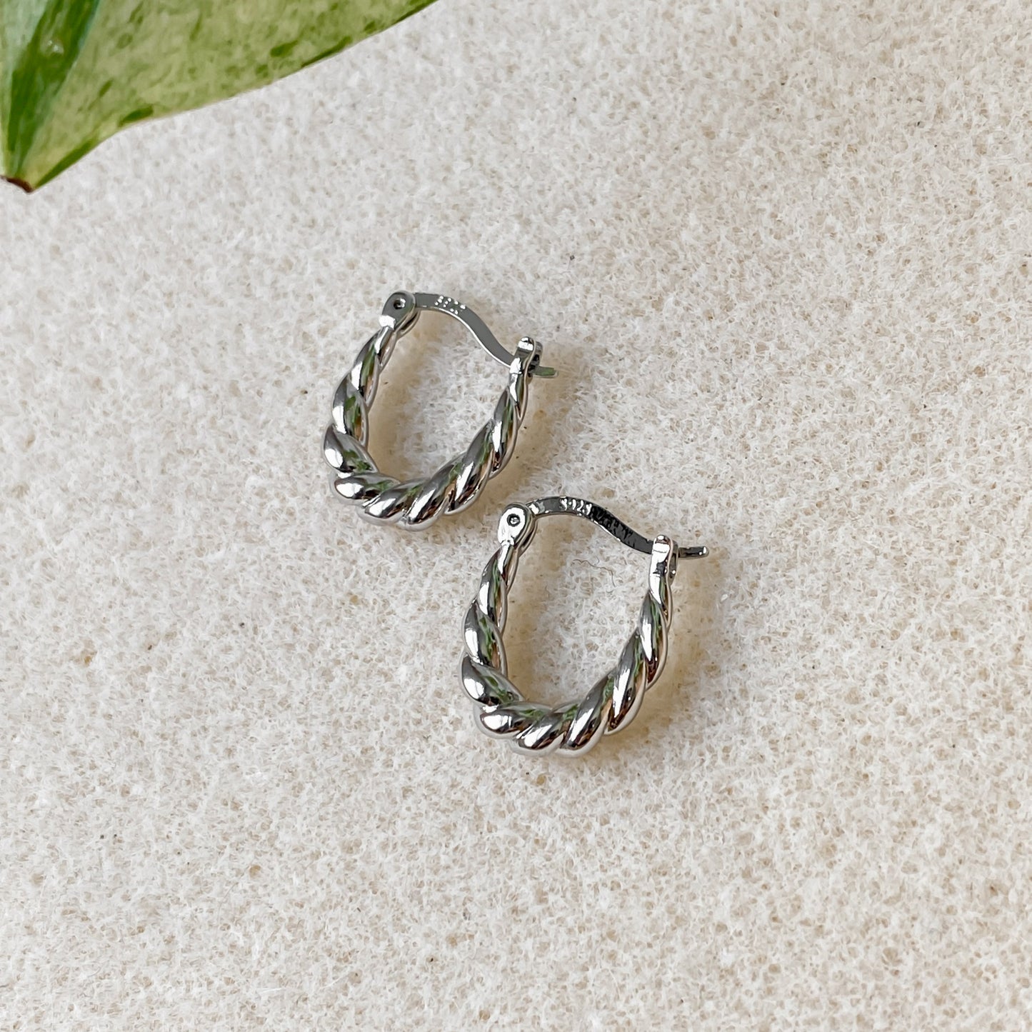 Boucles d’oreilles créoles torsadées en argent 925 Héra posées sur fond clair