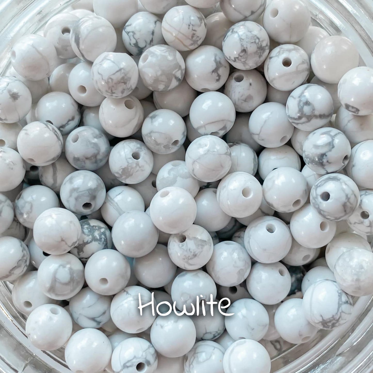 Gros plan sur la pierre de howlite, présentant ses motifs blancs marbrés avec des veines grises.