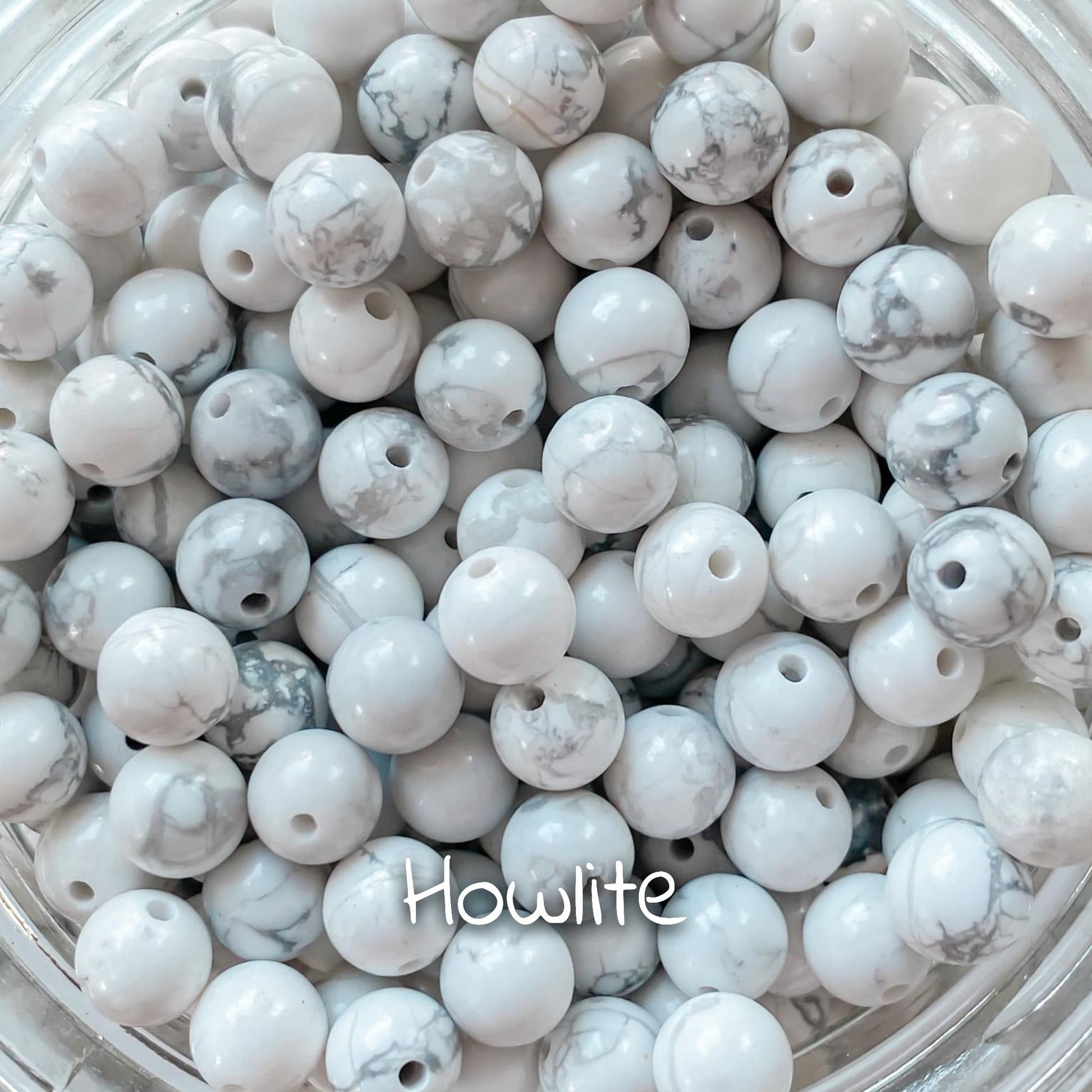 Gros plan sur la pierre de howlite, présentant ses motifs blancs marbrés avec des veines grises.