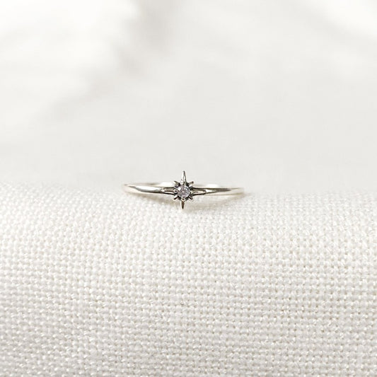 Bague minimaliste en Argent Sterling 925 avec une étoile pleine au centre, ornée d'un zircon lumineux, portée sur le majeur en combinaison avec d'autres bagues pour un look raffiné.