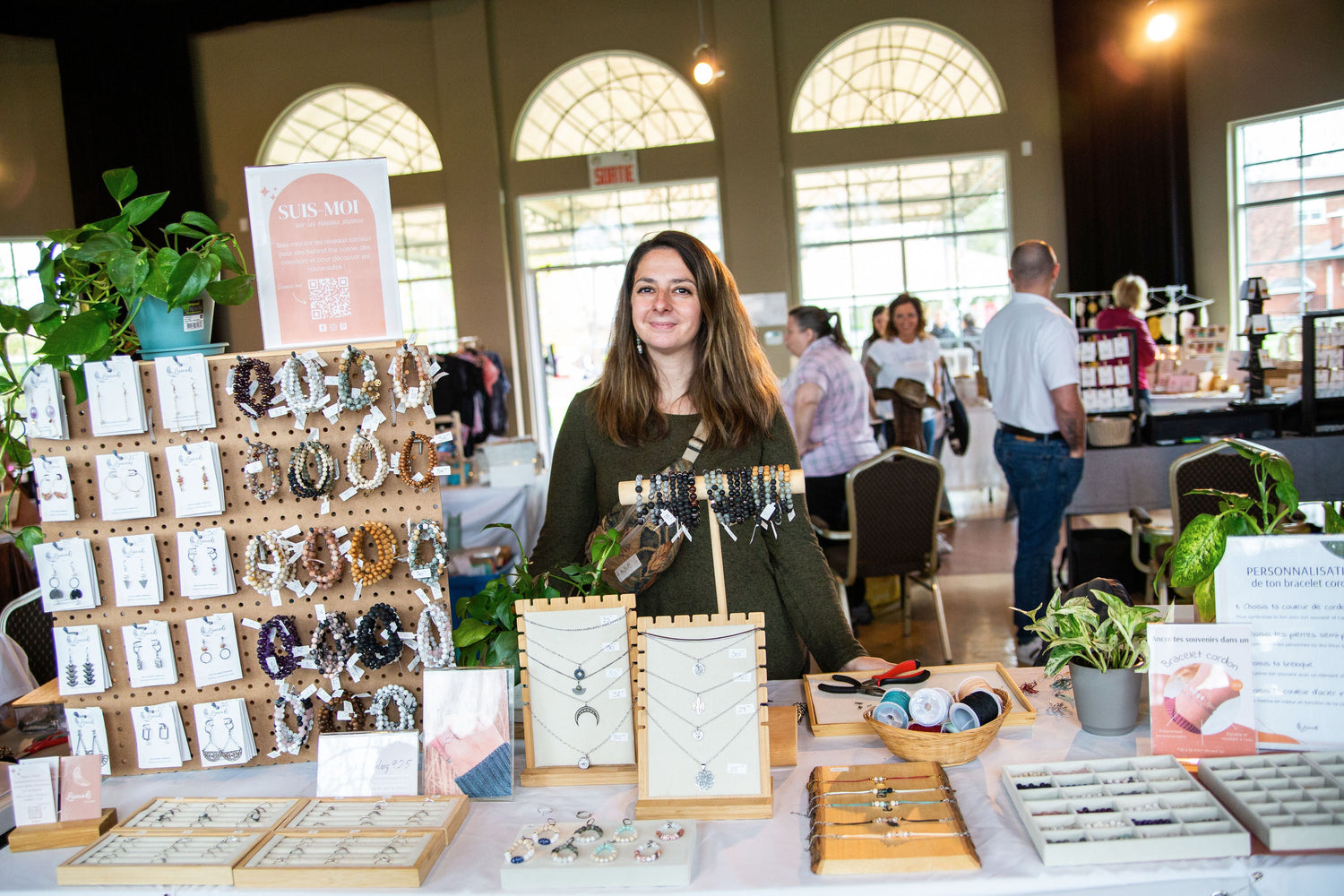 Alexia de Lunaki Design à sa table lors d’un marché d’artisans, présentant ses bijoux faits main en pierres naturelles.