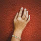 Bague Arabesque dorée portée devant un mur terracotta