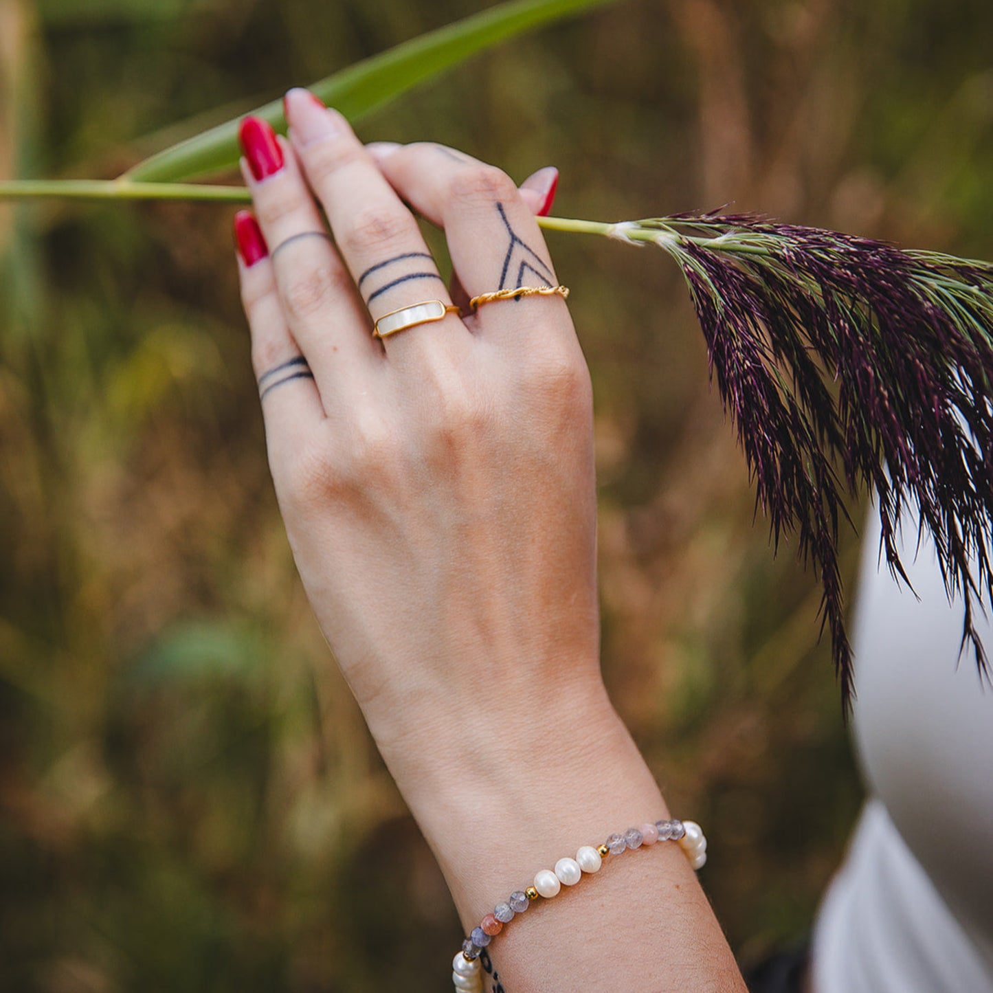 Bague Calypso dorée en nacre portée à la main avec bracelet pierres naturelles