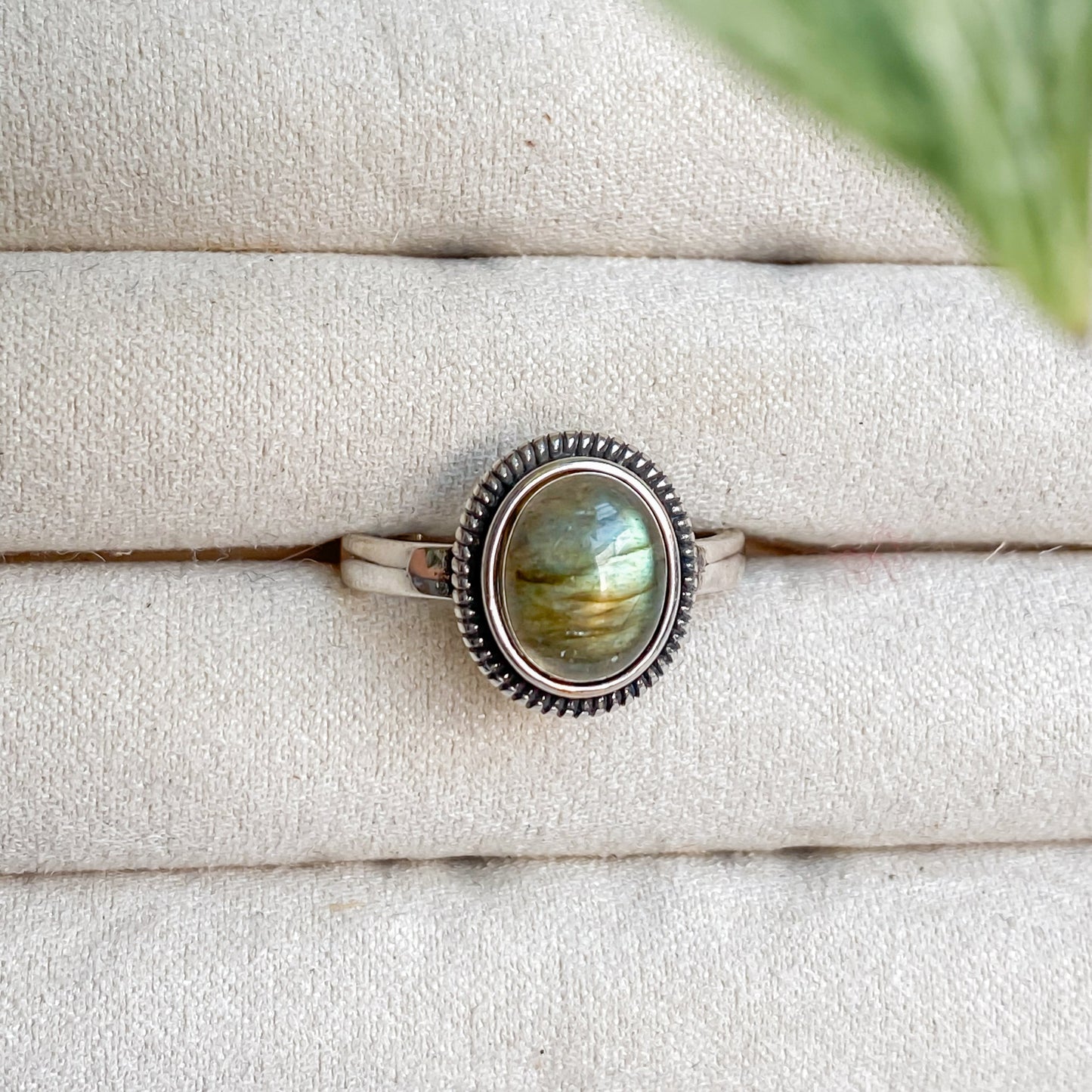 Bague Morgane en argent sterling 925 et labradorite naturelle posée sur un présentoir clair, reflets verts et dorés.