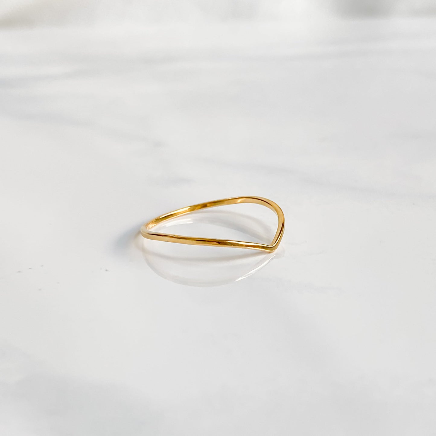 Bague minimaliste dorée Bellona en acier inoxydable, fine et résistante, posée à plat.