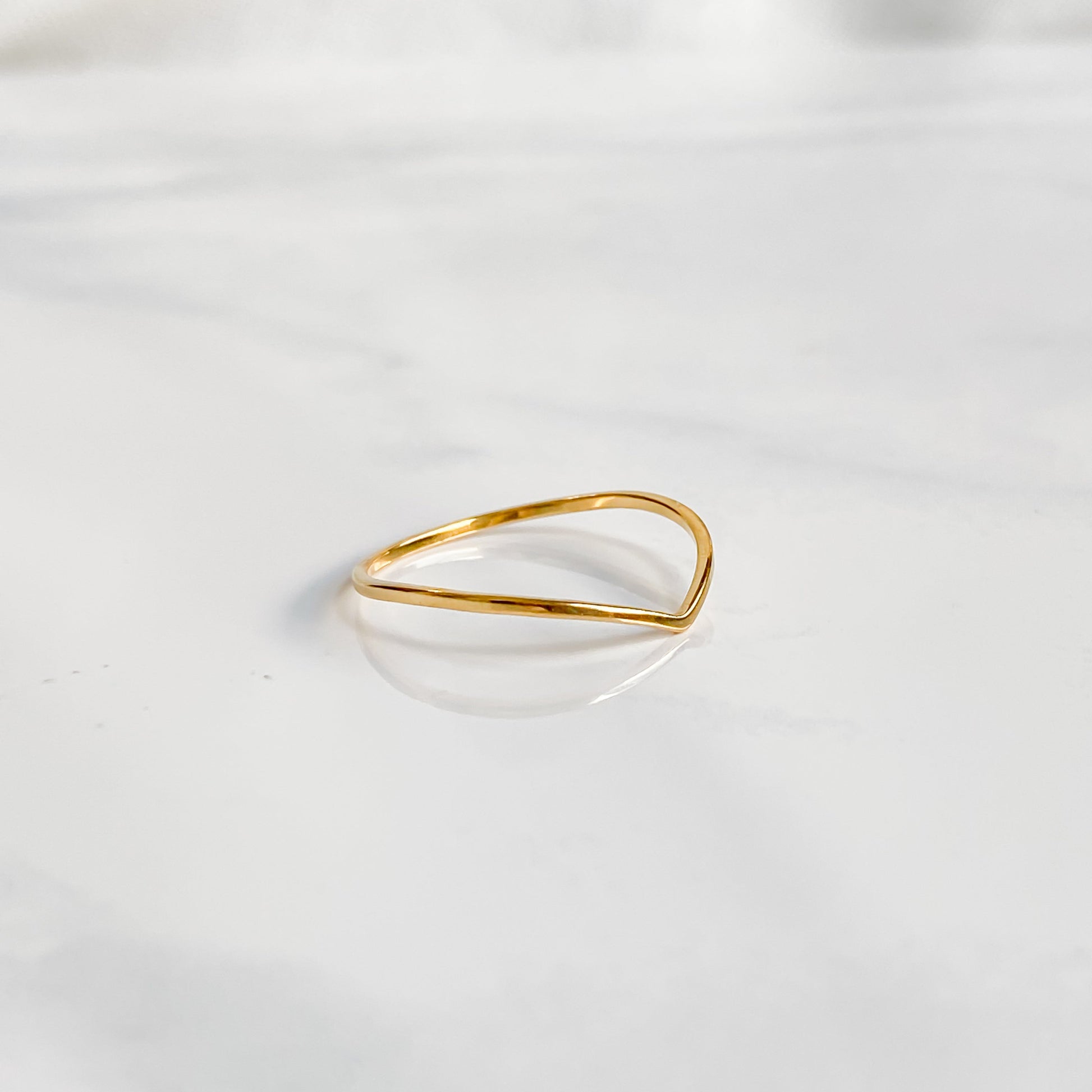 Bague minimaliste dorée Bellona en acier inoxydable, fine et résistante, posée à plat.