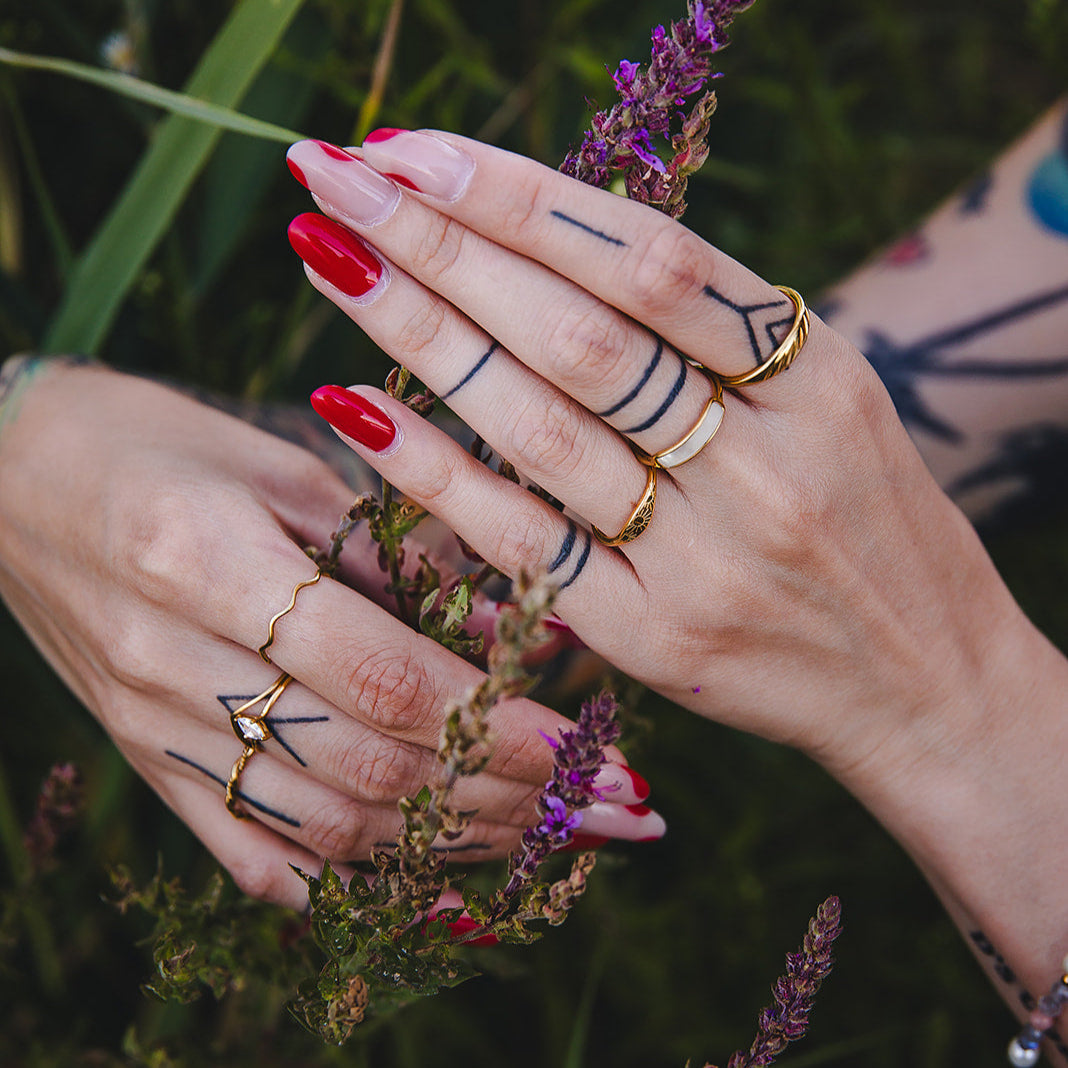 Bague ondulée dorée Naïa photographiée en extérieur au milieu des fleurs