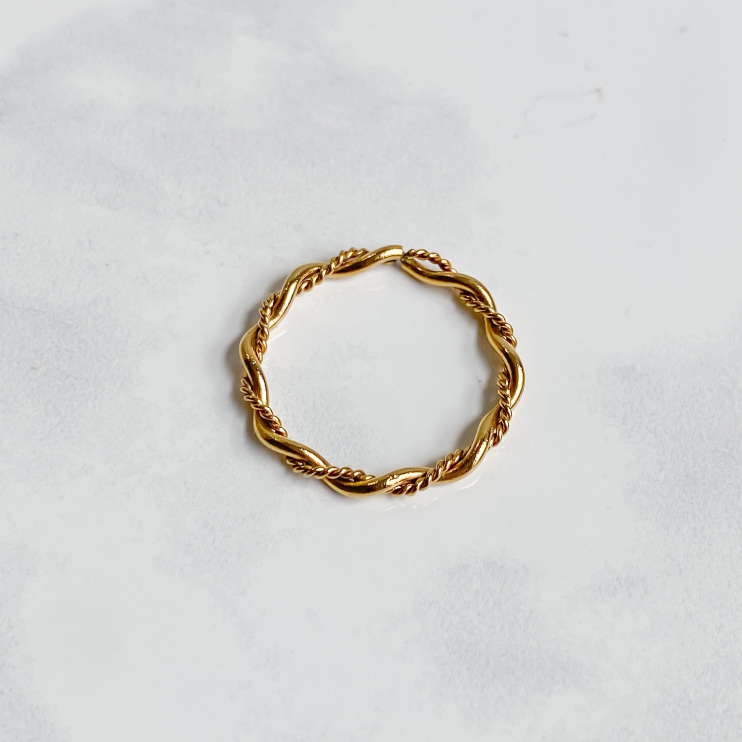 Bague Rhéa torsadée en acier inoxydable plaqué or 18K, vue du dessus sur fond blanc.
