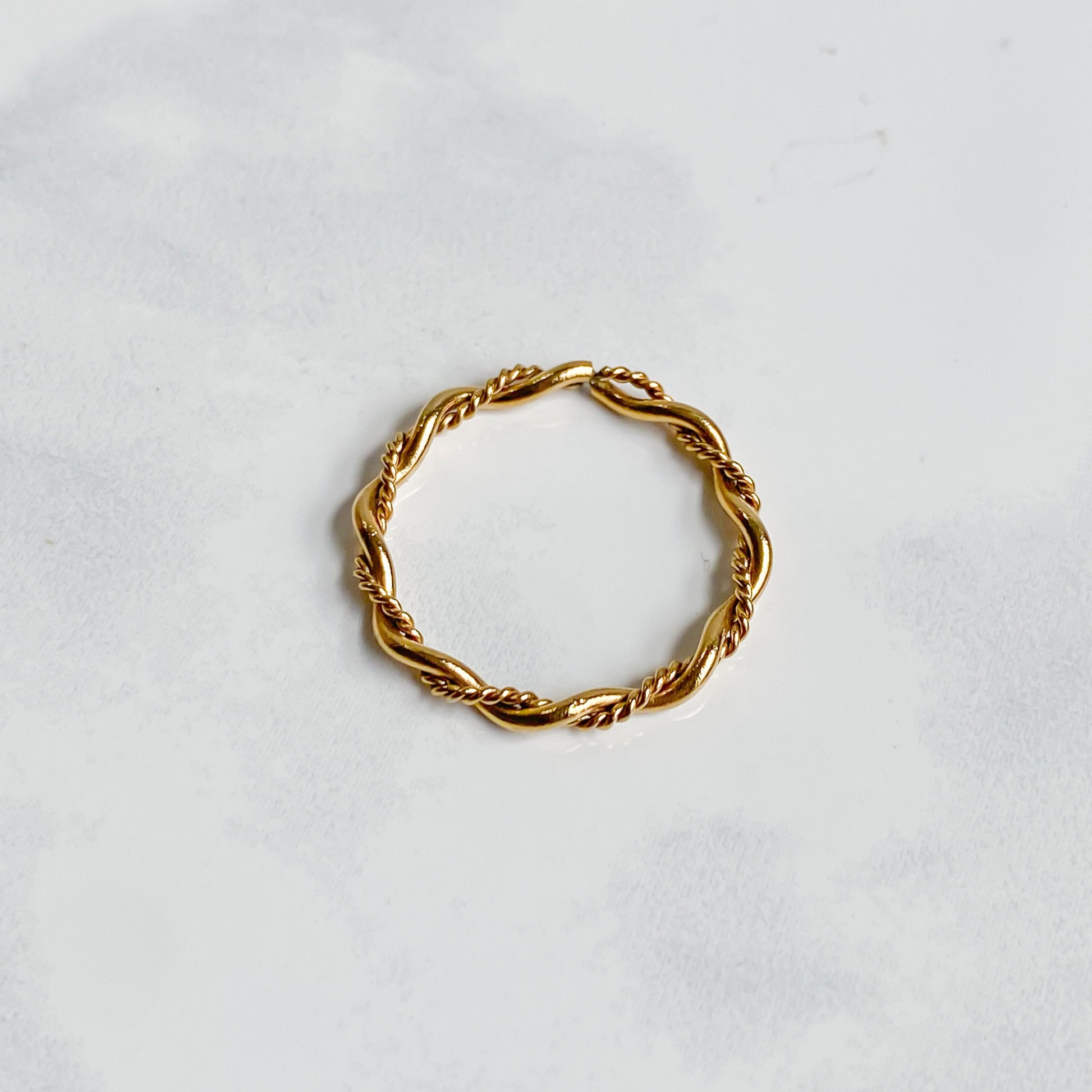 Bague Rhéa torsadée en acier inoxydable plaqué or 18K, vue du dessus sur fond blanc.