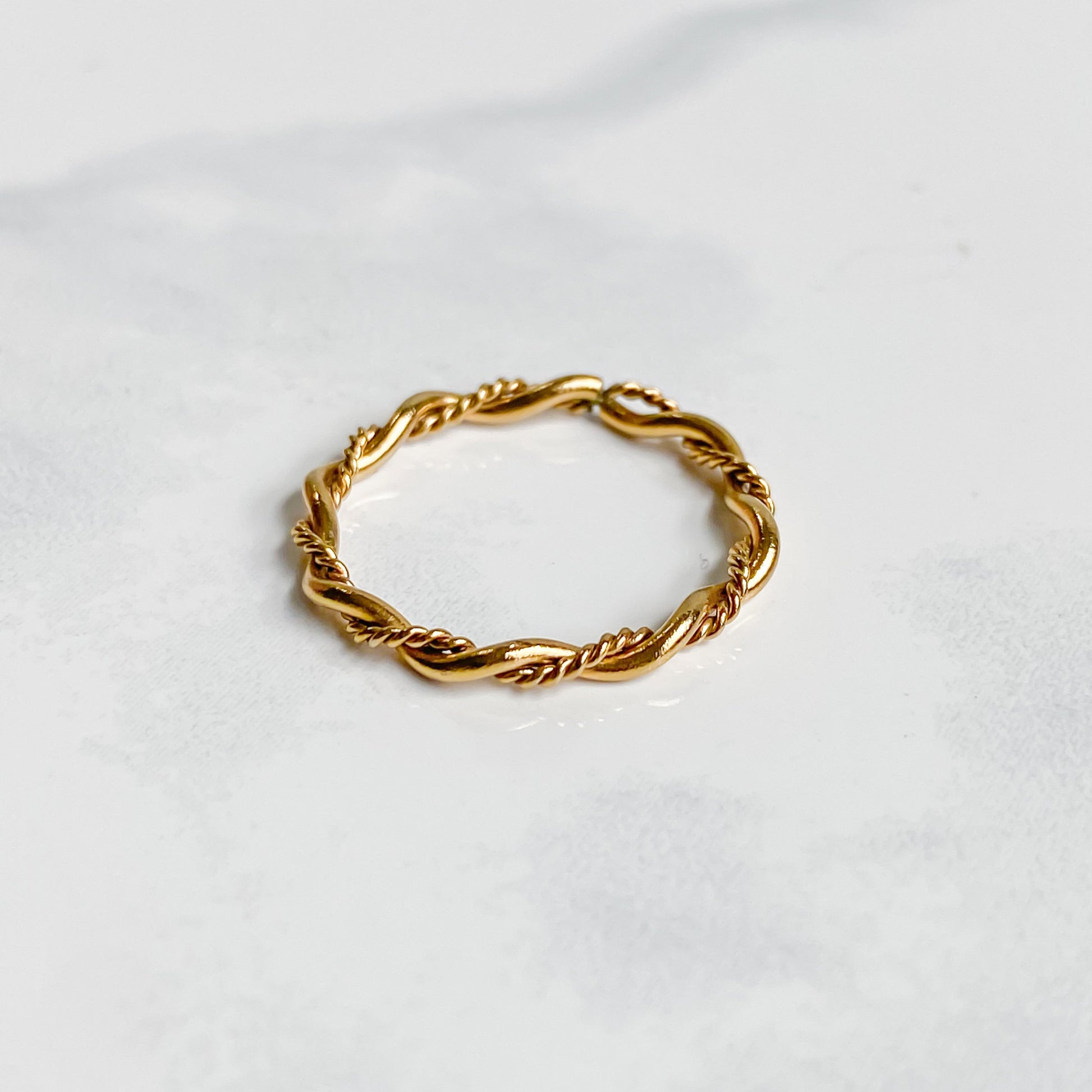 Bague Rhéa fine et minimaliste en acier inoxydable plaqué or 18K, vue inclinée sur fond blanc.