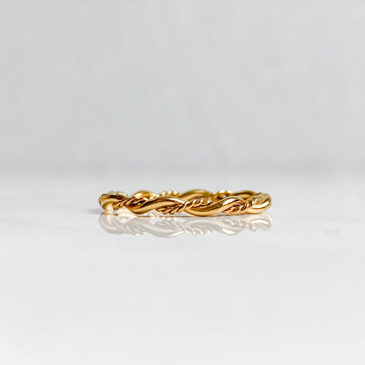 Bague Rhéa torsadée en acier inoxydable plaqué or 18K, vue de profil posée à plat.