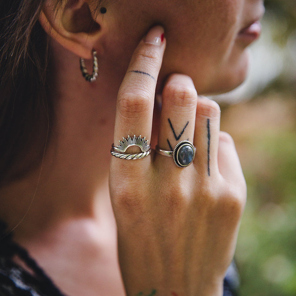 Main portant plusieurs bagues en argent, dont la bague torsadée Sylva 925, accumulation de bijoux.