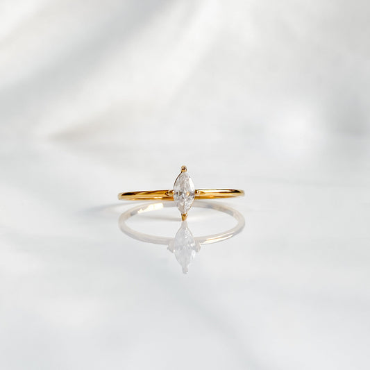 Gros plan sur la bague solitaire Venus, zircon blanc lumineux monté sur anneau doré minimaliste.