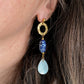 Boucles d’oreilles Abalone portées en gros plan, avec cercle doré martelé, perle ovale en céramique bleue et pendentif en nacre naturelle en forme de goutte.