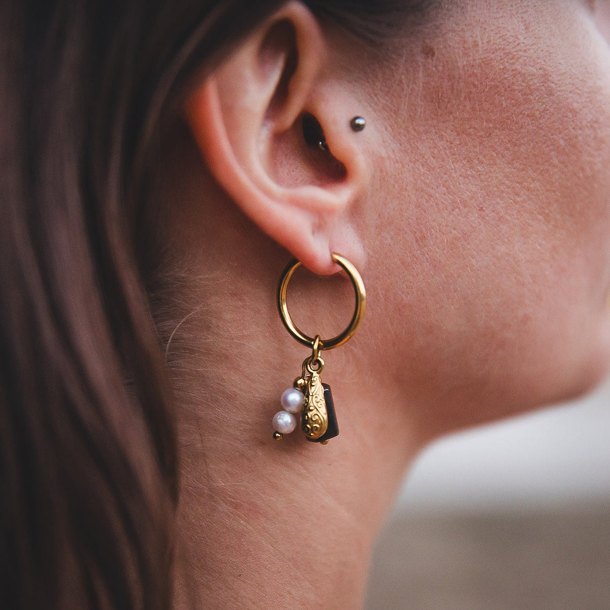 Gros plan des boucles d’oreilles Azalaï dorées portées