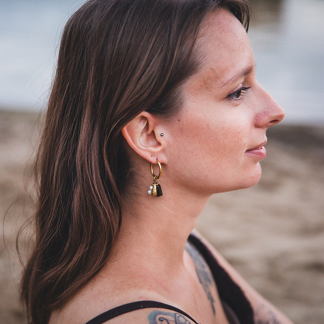 Boucles d’oreilles Azalaï dorées portées sur une plage