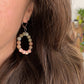 Boucle d’oreille pendante Capri portée à l’oreille, en labradorite, pierre de soleil et céramique fleurie rouge – bijou fait main à Montréal.