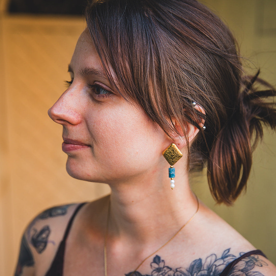 Boucles d’oreilles pendantes Chaouen dorées portées par un modèle