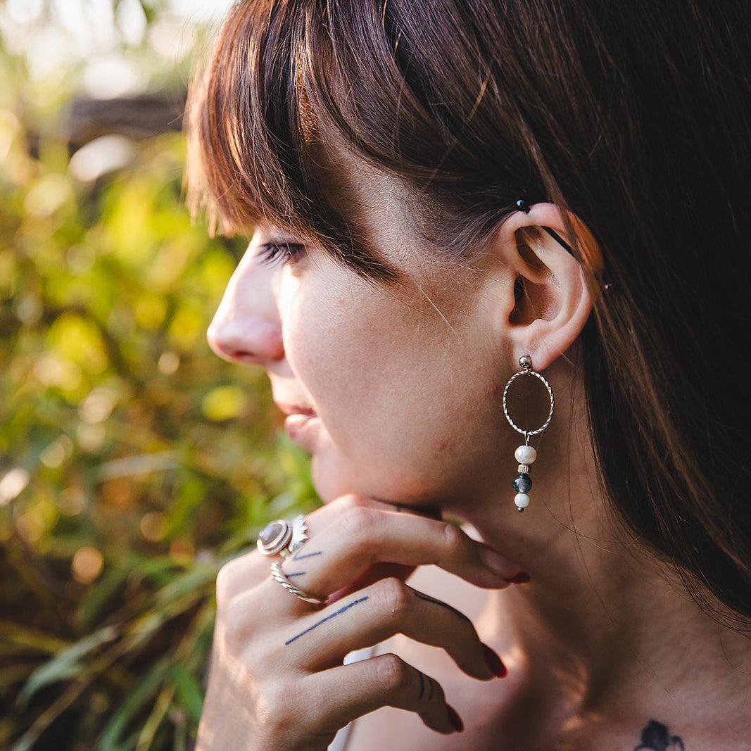 Gros plan sur les boucles d’oreilles Chloris en acier inoxydable argenté avec jade maotien, agate mousse et perle blanche.