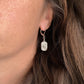 Boucles d’oreilles pendantes Estrella en acier inoxydable argenté portées à l’oreille – bijou artisanal et minimaliste