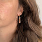 Boucles d’oreilles en pierres naturelles Hanami portées à l’oreille, avec quartz clair, pierre de soleil et bille de céramique florale rouge