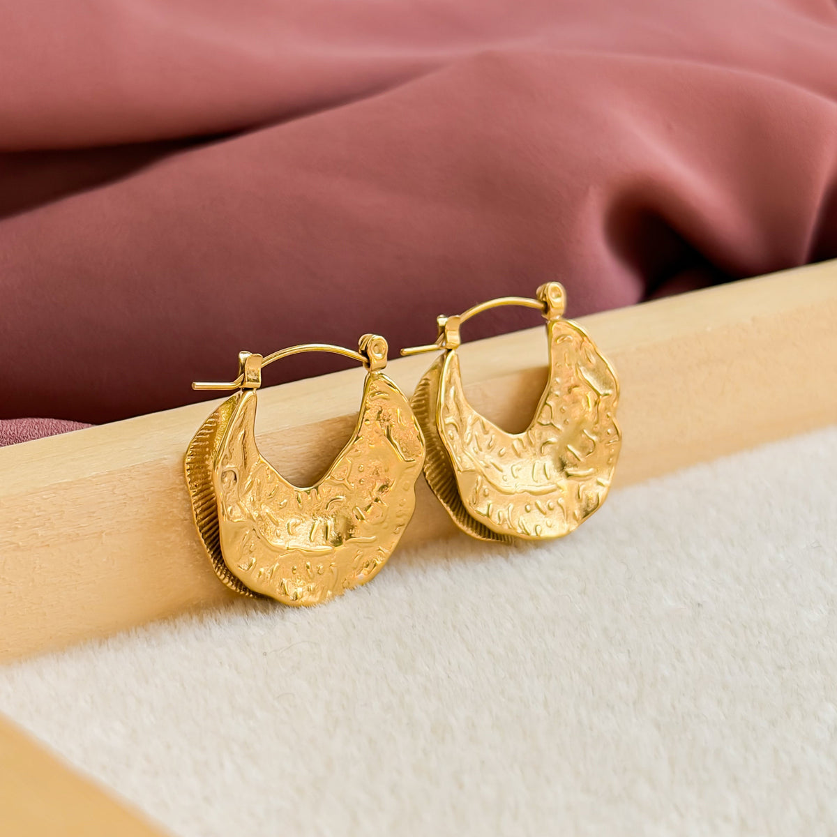 Boucles d’oreilles Medina dorées présentées dans l’univers de la collection Oasis
