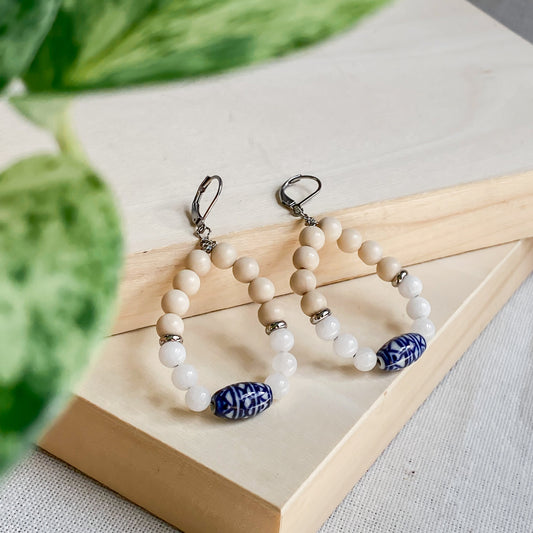 Boucles d’oreilles pendantes Naxos bohèmes en pierres naturelles et céramique bleue sur support bois.
