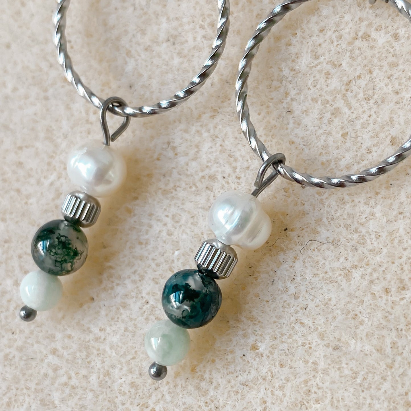 Gros plan sur les boucles d’oreilles Chloris en acier inoxydable argenté et pierres semi-précieuses.