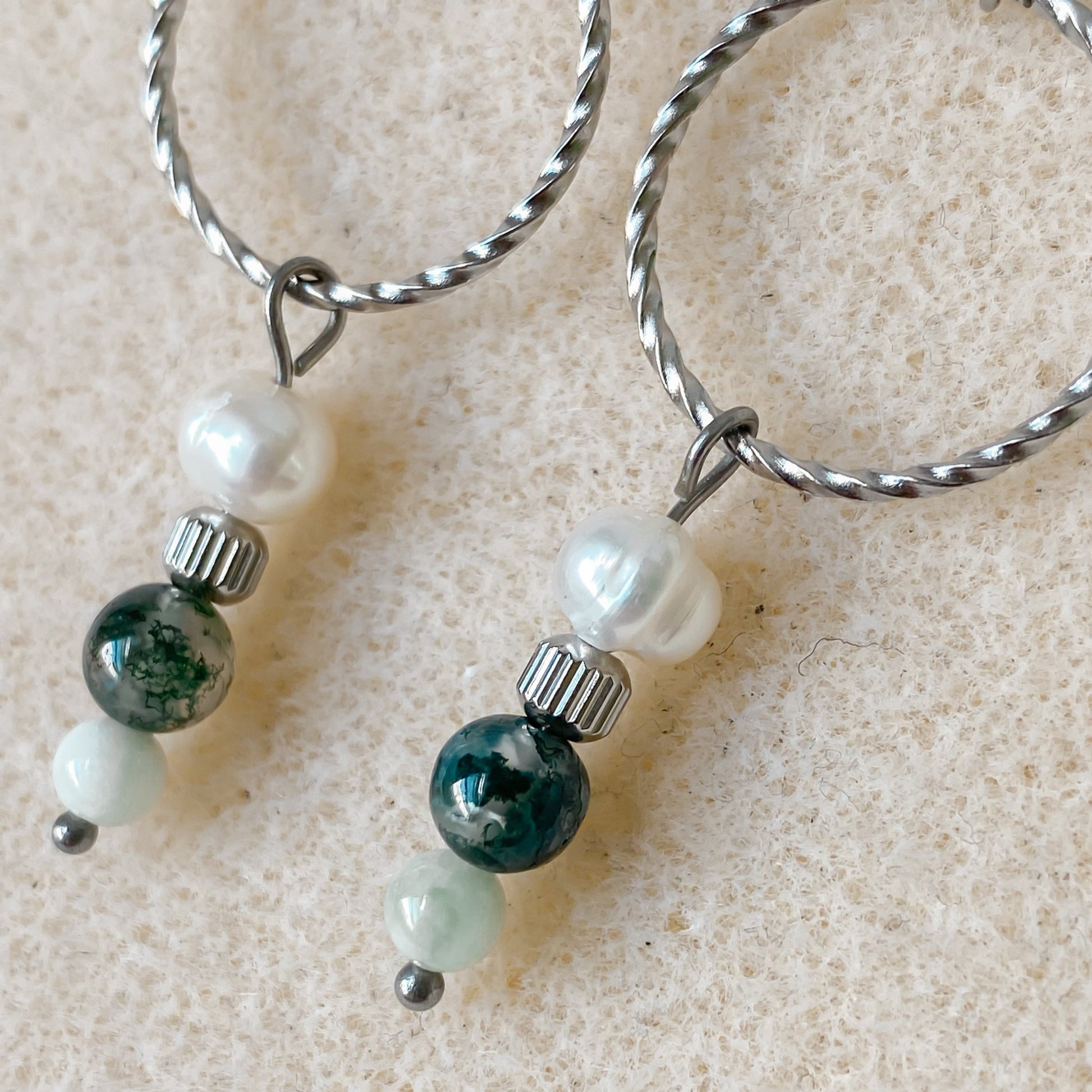 Gros plan sur les boucles d’oreilles Chloris en acier inoxydable argenté et pierres semi-précieuses.