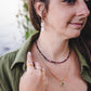 Femme de profil portant les boucles d’oreilles pendantes Phoebe en pierre de lune arc-en-ciel et acier inoxydable doré.