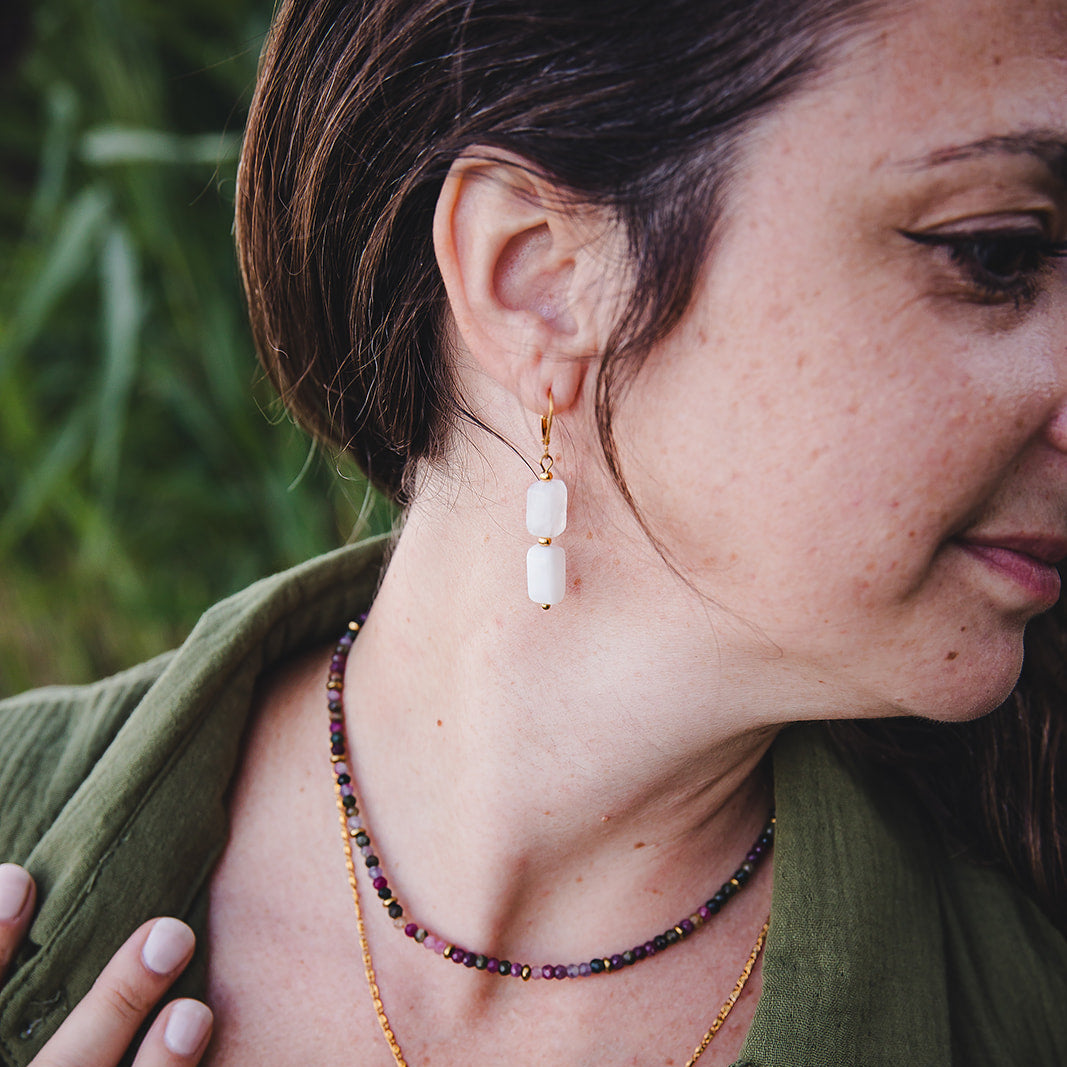 Boucles d’oreilles Phoebe en pierre de lune portées avec colliers dorés, photo de style bohème et naturel.